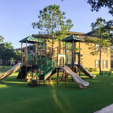 A children's play structure on a lawn in a residential area.